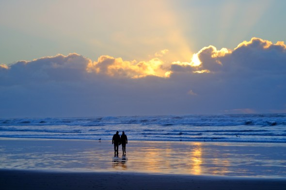 Silhouette of couple walking toward setting sun on an Oregon beach