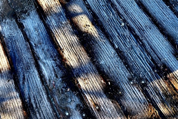 Detail of frost-covered wooden boardwalk in sun and shadow
