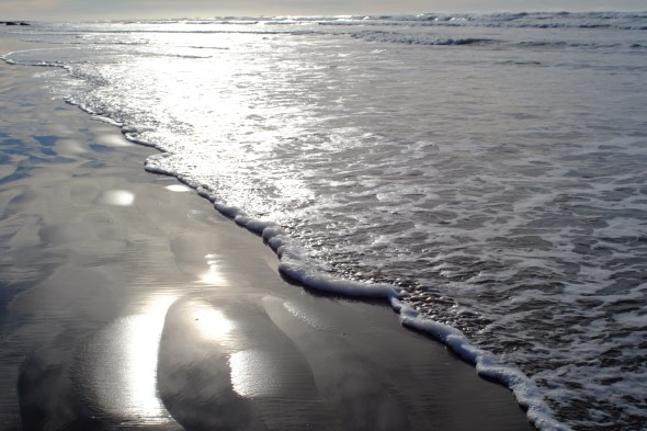 Water's edge, surf and sun reflected on an Oregon beach