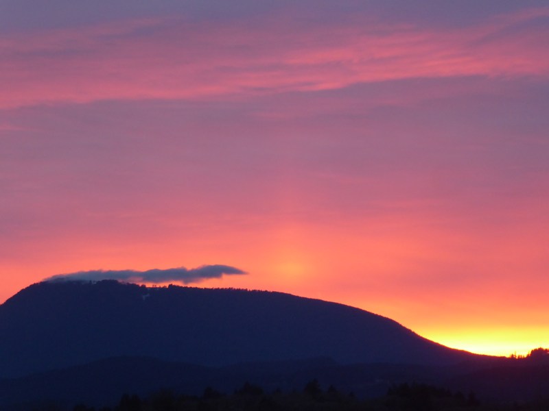 Pink and purple pastel sky above silhouetted mountain after sunset
