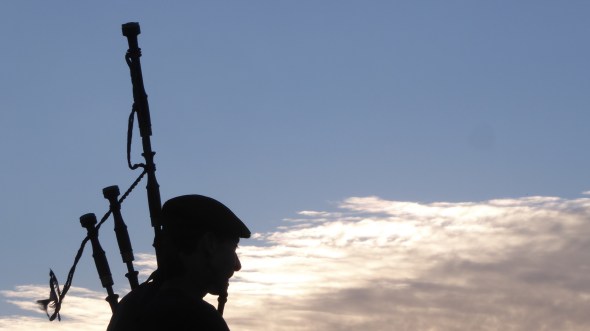 Silhouette of bagpiper with blue sky and glowing clouds in background