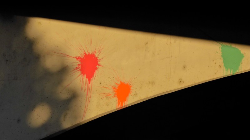 Red, orange and green paintball splashes on concrete overpass