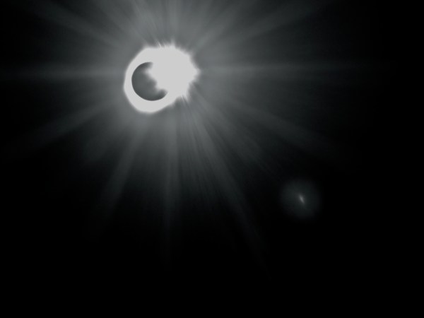 Total solar eclipse with bright flash at upper right