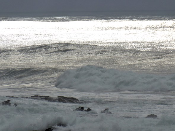 Ocean waves, offshore rocks and grey sky