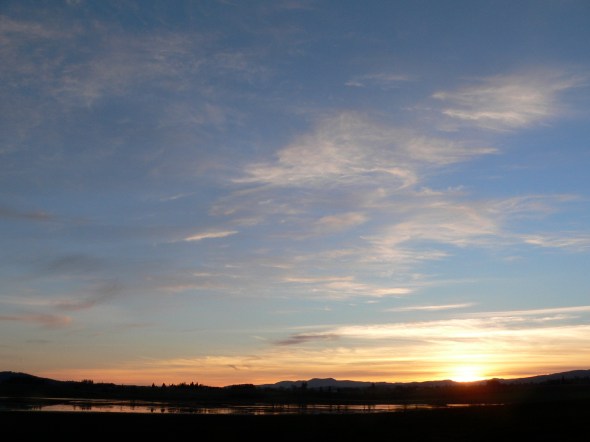Sunset with bright clouds in sky over wetlands lansdcape