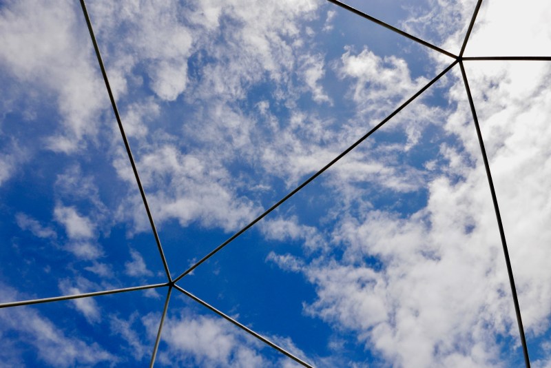 Blue sky and white clouds framed by triangular shapes
