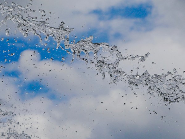 Water droplets with blue sky and white clouds behind
