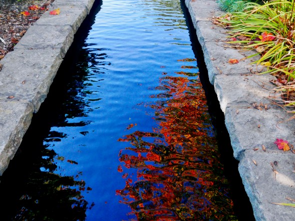 Small canal with orange leaves reflected in the water