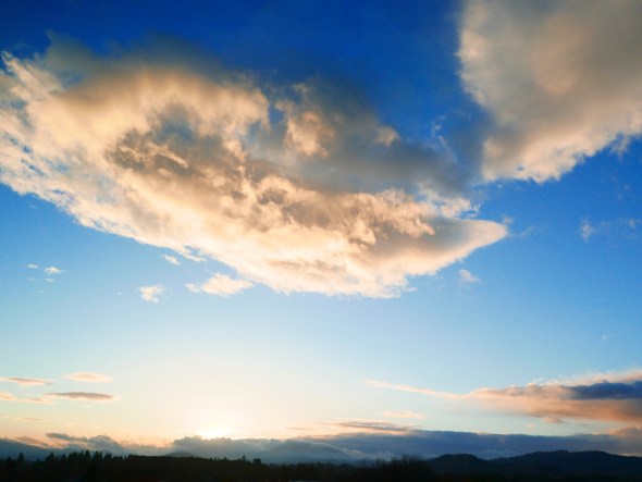 Glowing white cloud in blue sky and dark horizon