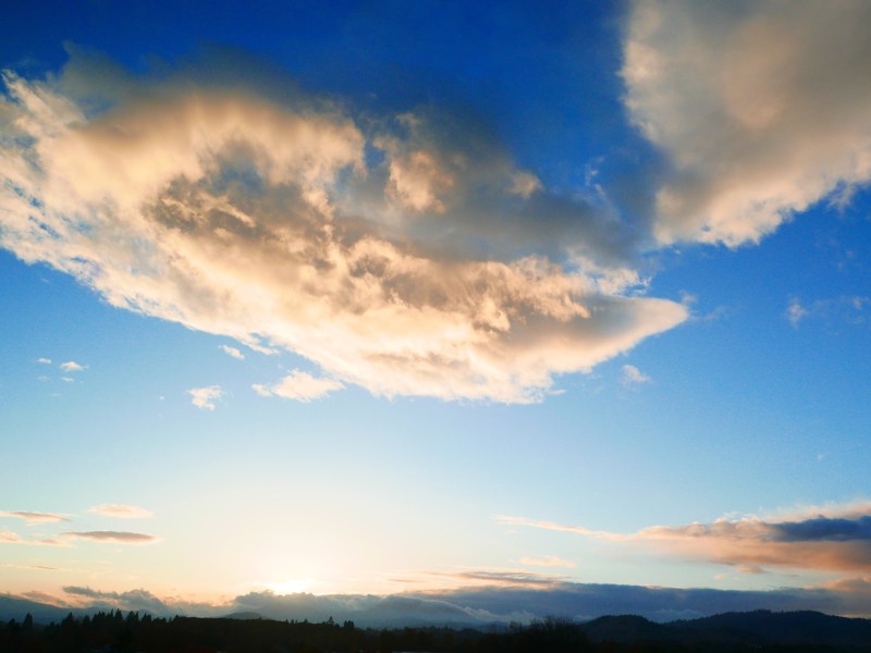 Glowing white cloud in blue sky and dark horizon