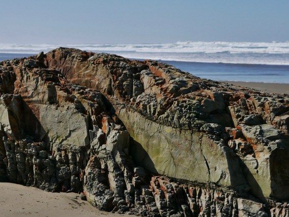 Rock outcrop on beach with surf