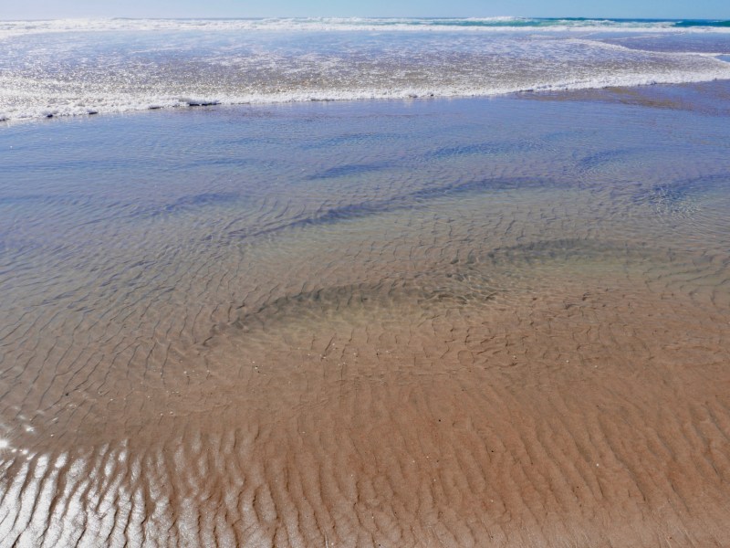 Ripples in sand and surf in distance
