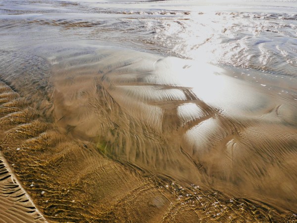 Beach with ripples, sunlight and sand patterns