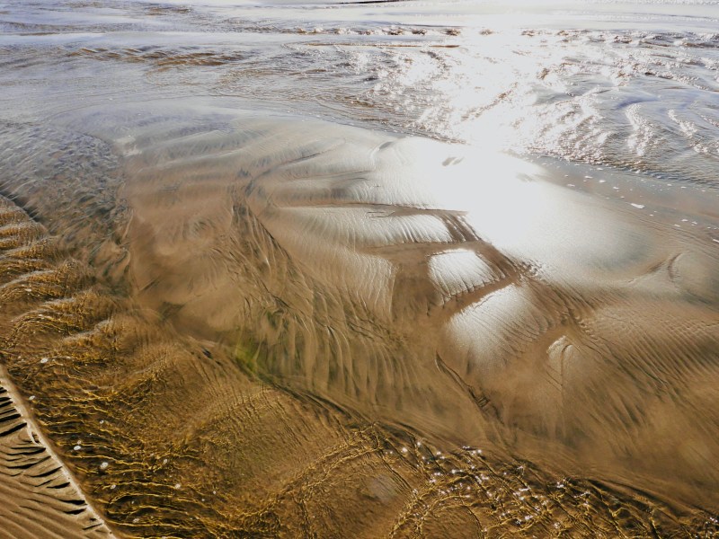 Beach with ripples, sunlight and sand patterns