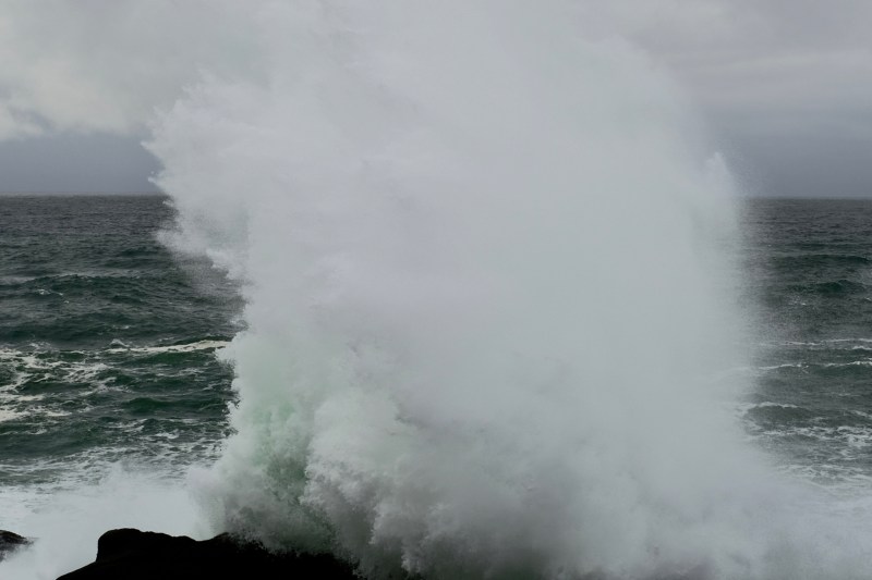 Spray high in air as breaking wave hits rocky coastline