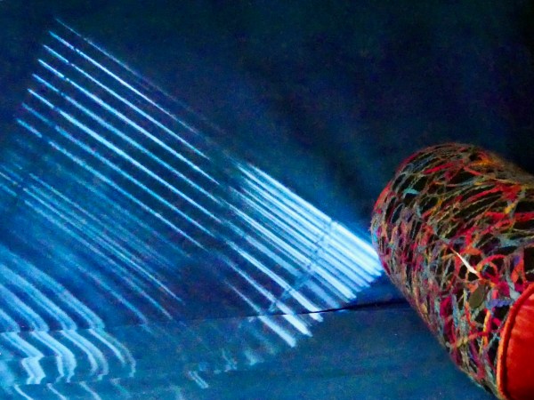 patterns of sun and shadow on blue futon and colorful pillow