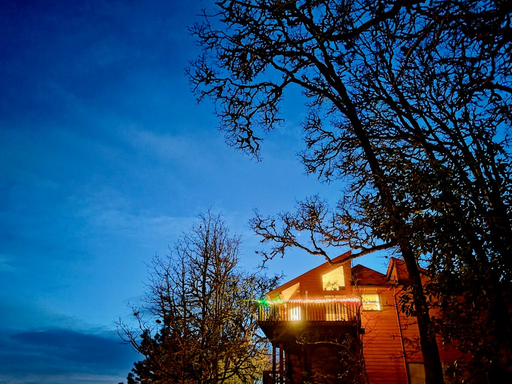 brightly lit house blue sky, bare oak trees and jupiter at dusk