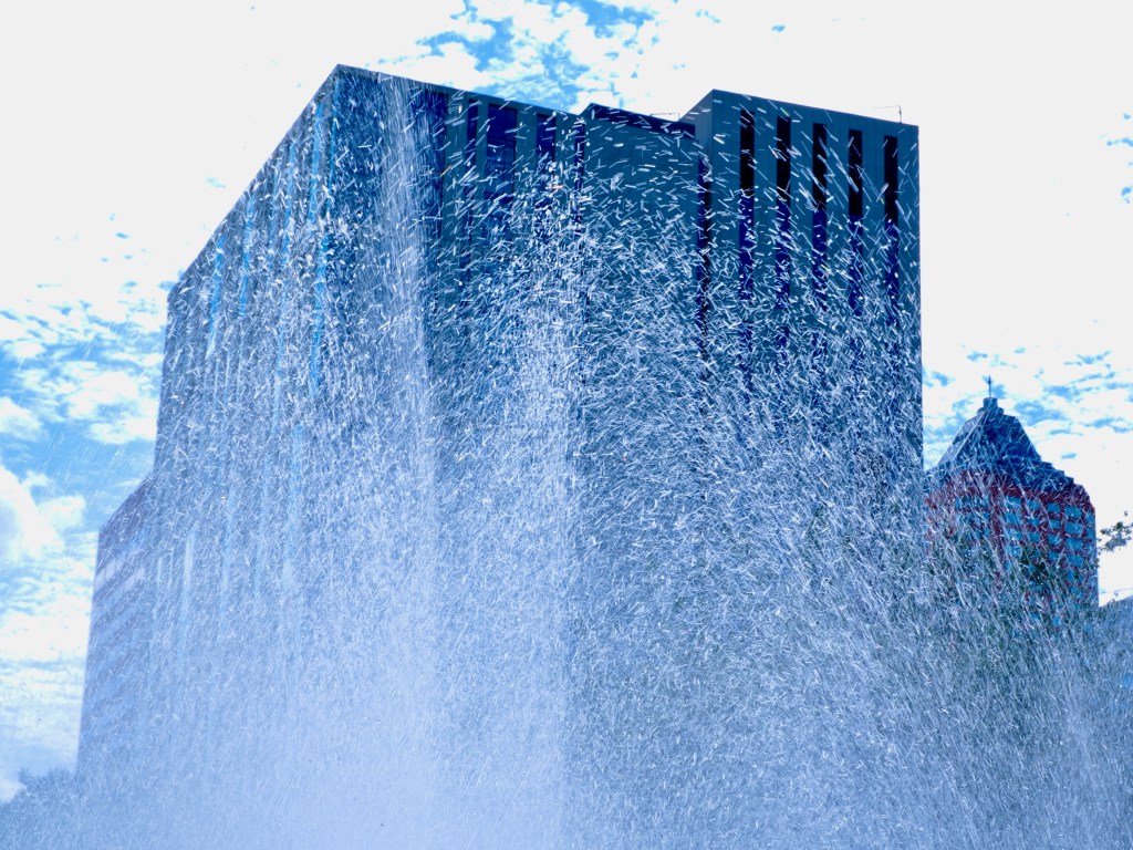 water from fountain in front of tall buildings
