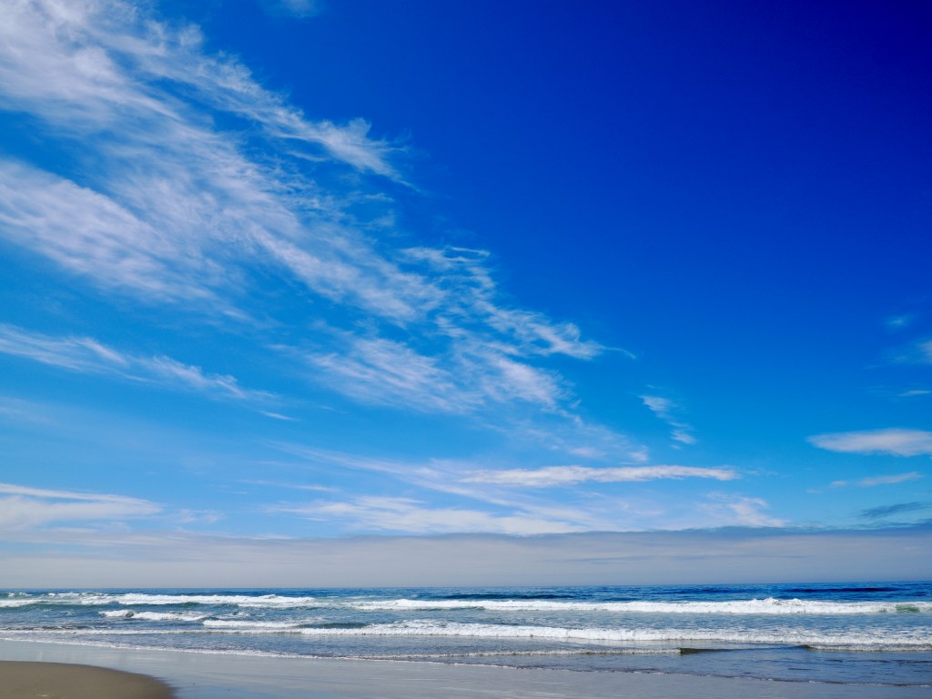 sandy beach, surf and blue sky with white clouds