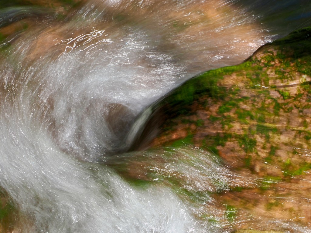 whitewater flowing over and around mossy rocks in a creek