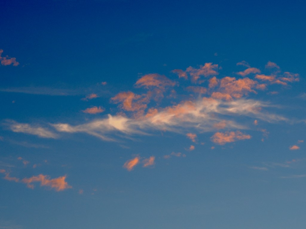 orange and white wispy clouds in blue sky